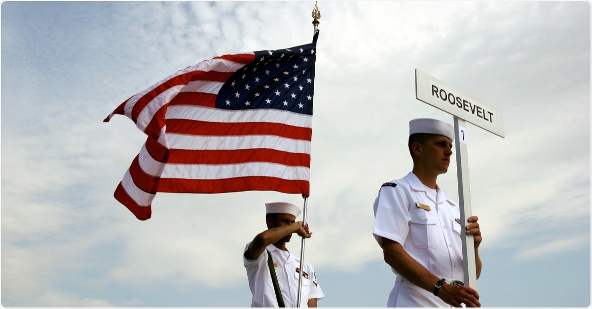 Study: An Outbreak of Covid-19 on an Aircraft Carrier. Image of American sailors with US flag - USS Theodore Roosevelt docked at the port of Taranto, Puglia, Italy. Image Credit: Massimo Todaro / Shutterstock