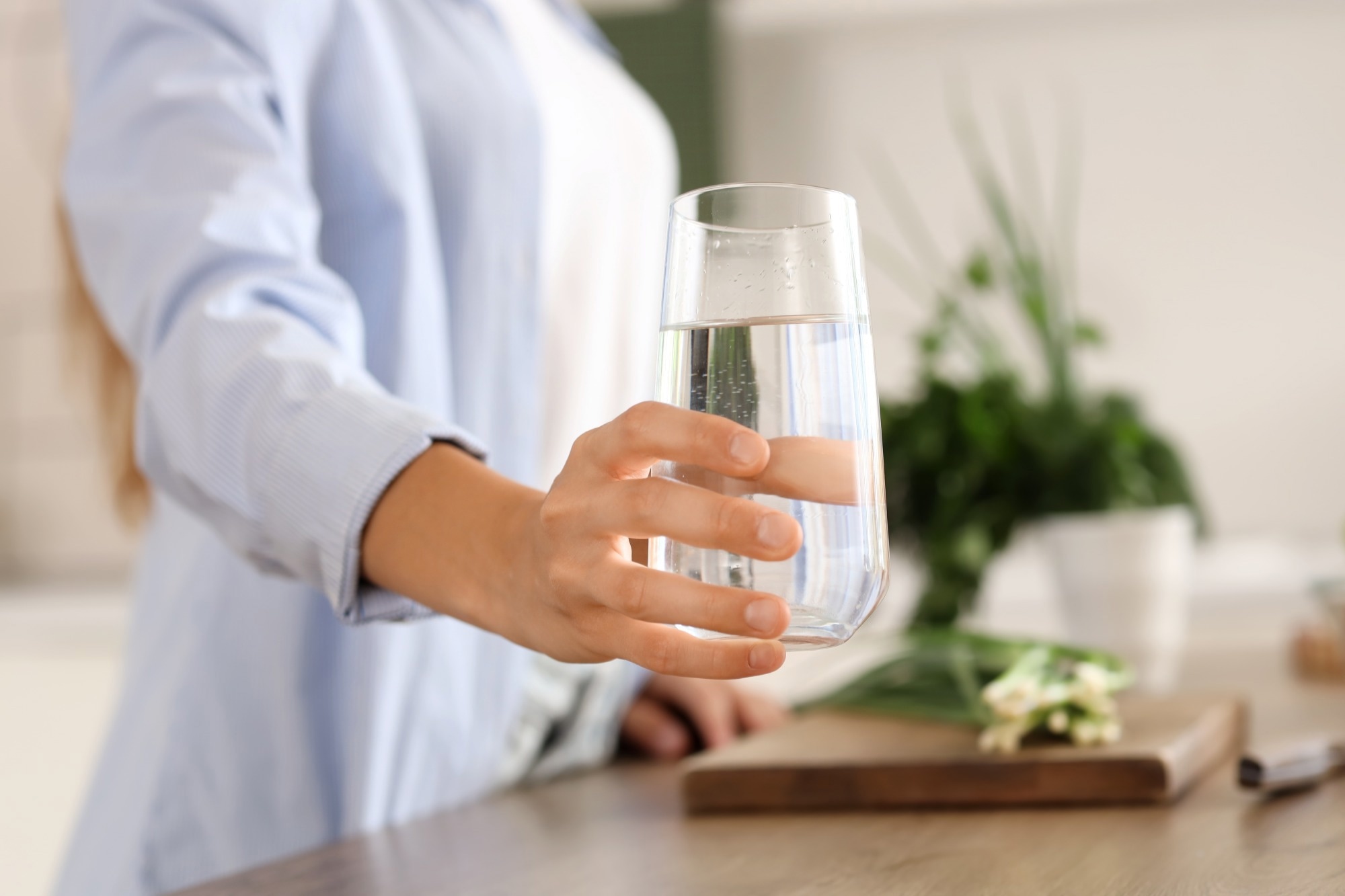 Young woman with glass of water in kitchen, closeup.