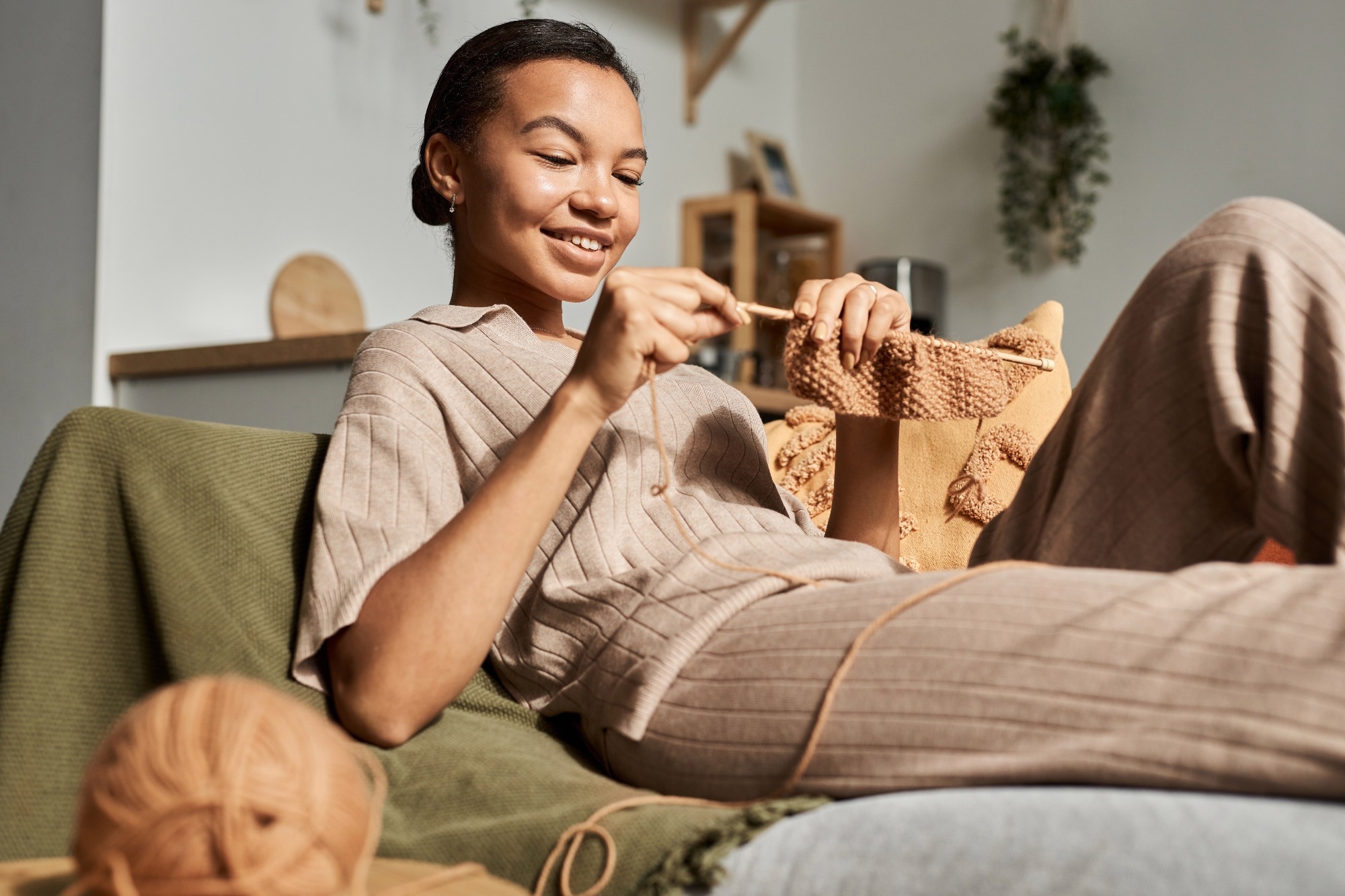 Portrait of Black young woman knitting at home in sunlight and enjoying cozy hobby, copy space.