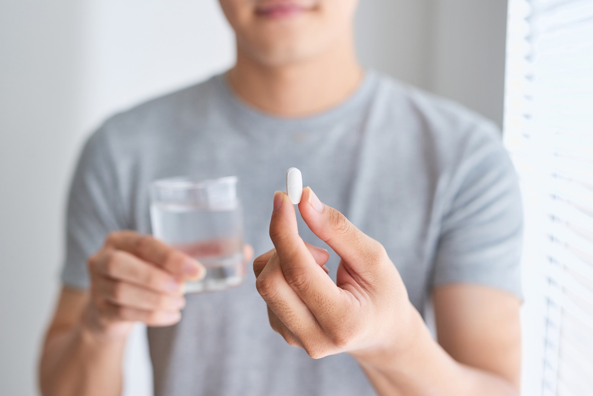 Man holding a pill and a glass of water