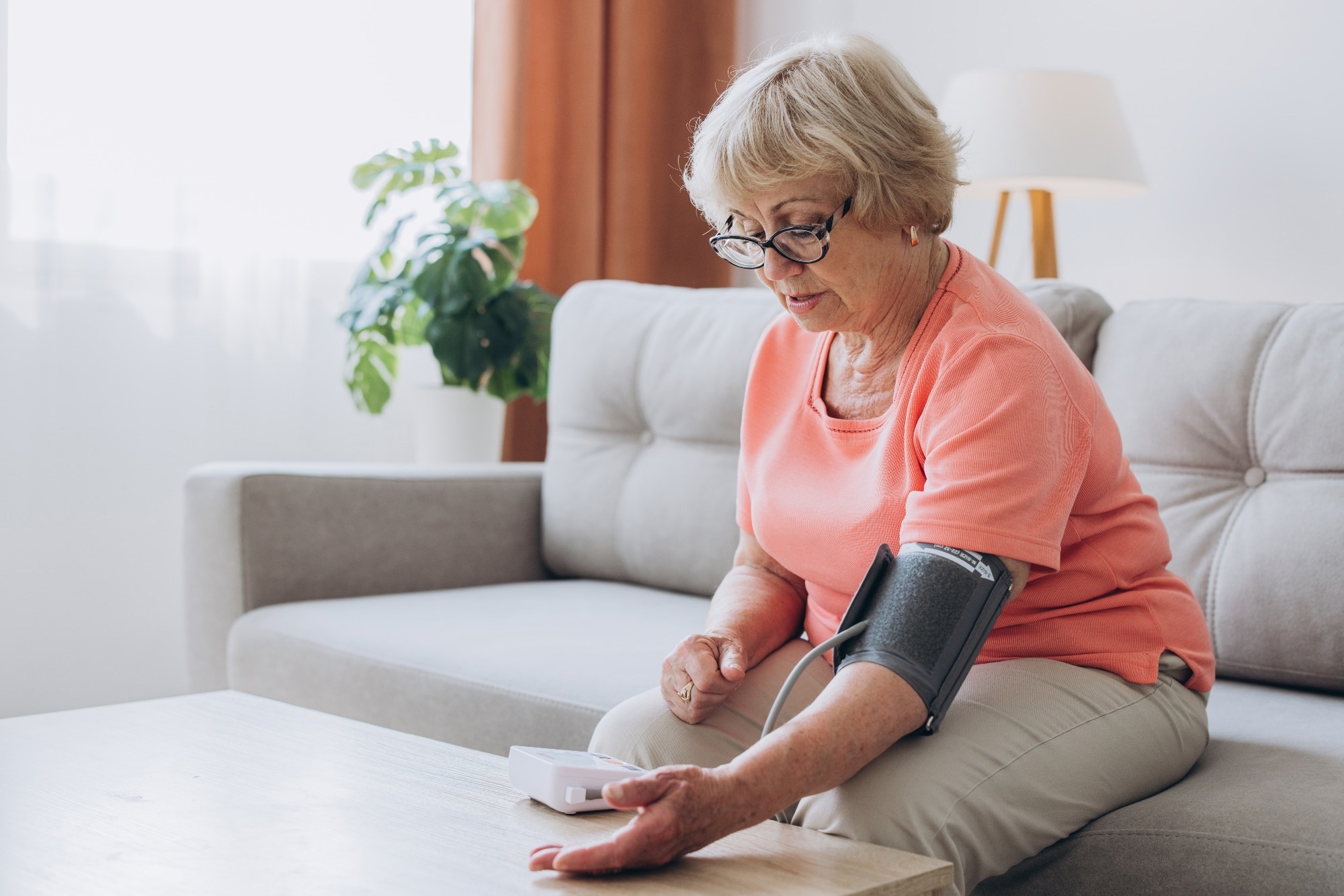 Senior woman with hypertension measuring blood pressure herself at home