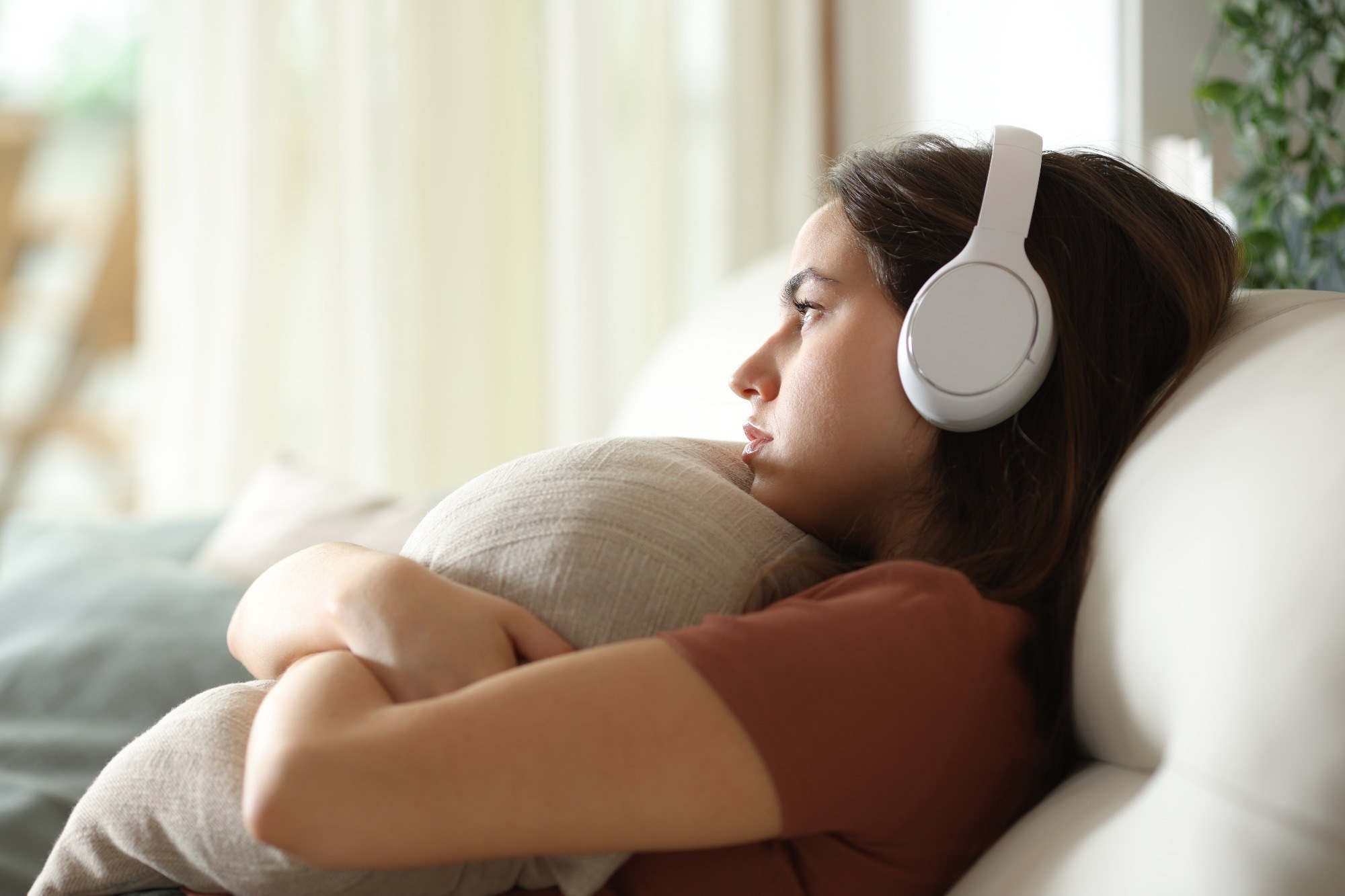 Sad and melancholic woman listening music with headphone at home