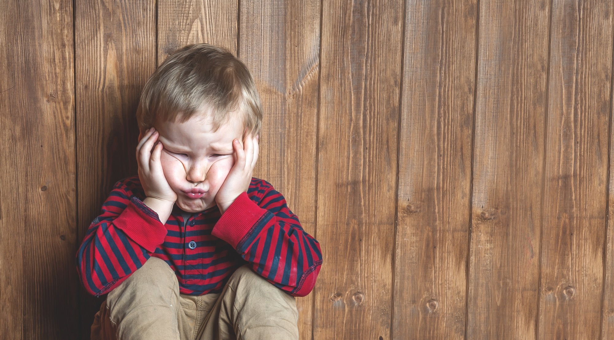 Stressed child covering ears and scrunching face