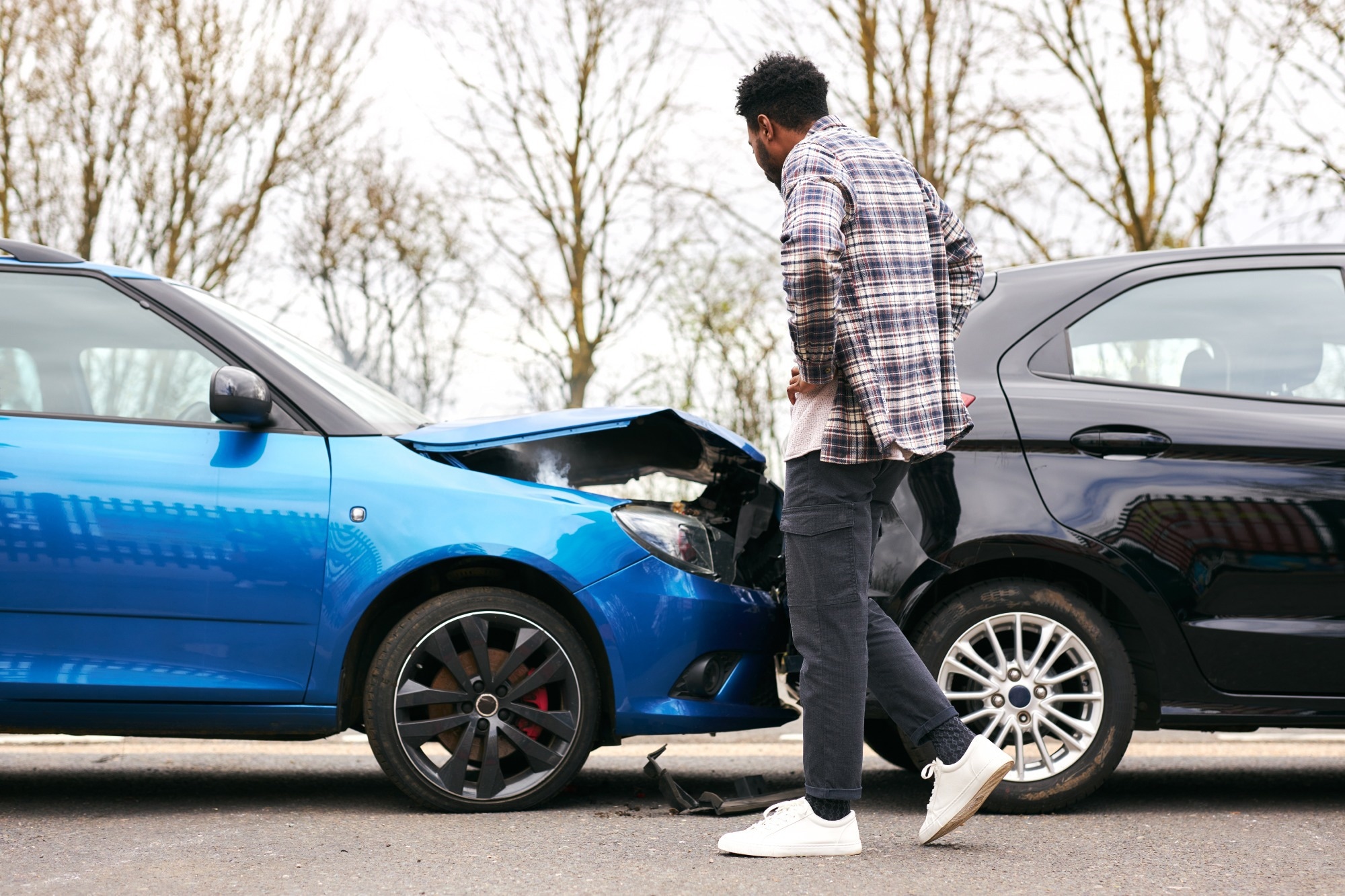 Young man looking at damaged car hit from behind after traffic accident