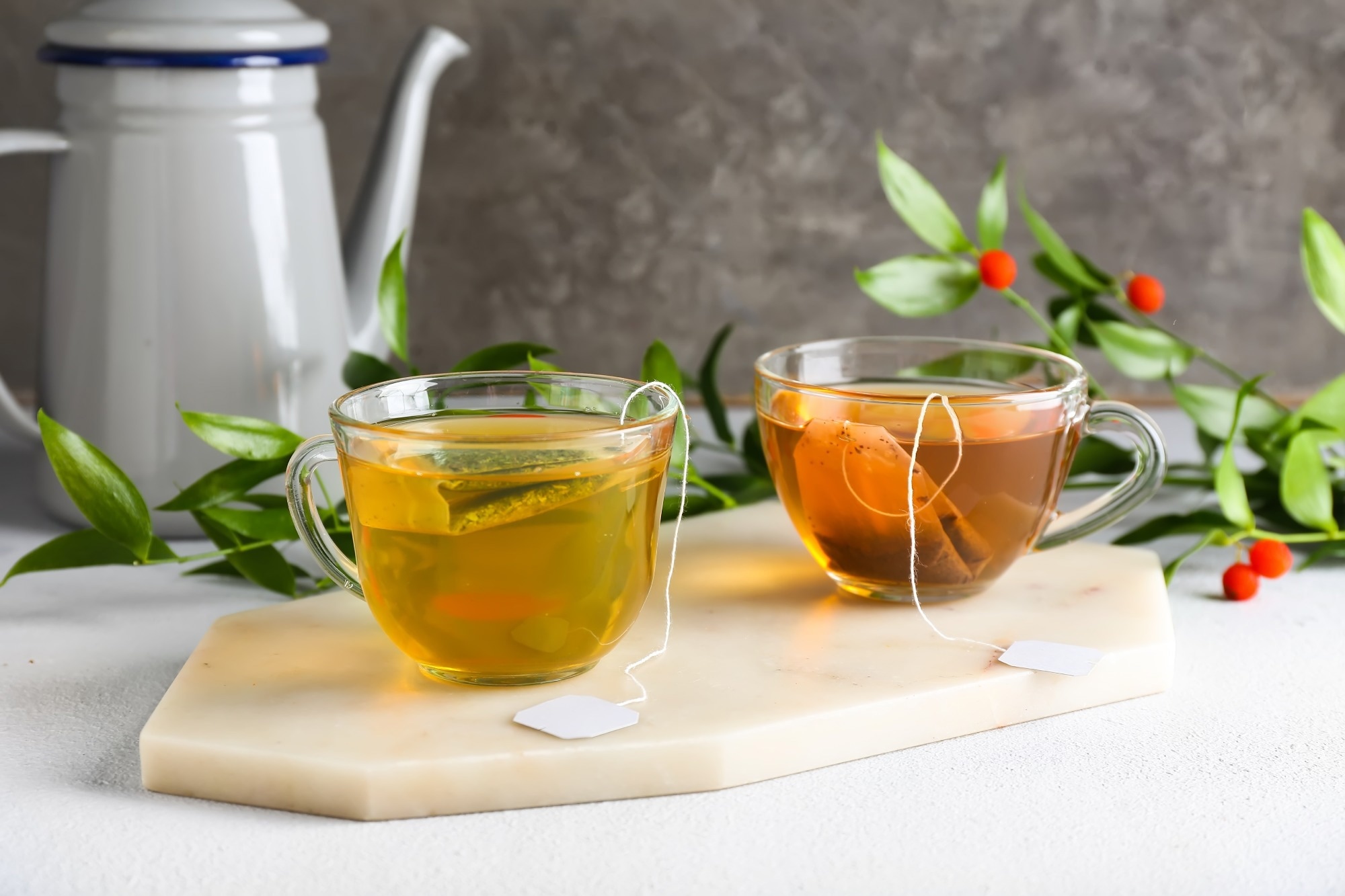 Cups of aromatic green and black tea on light background