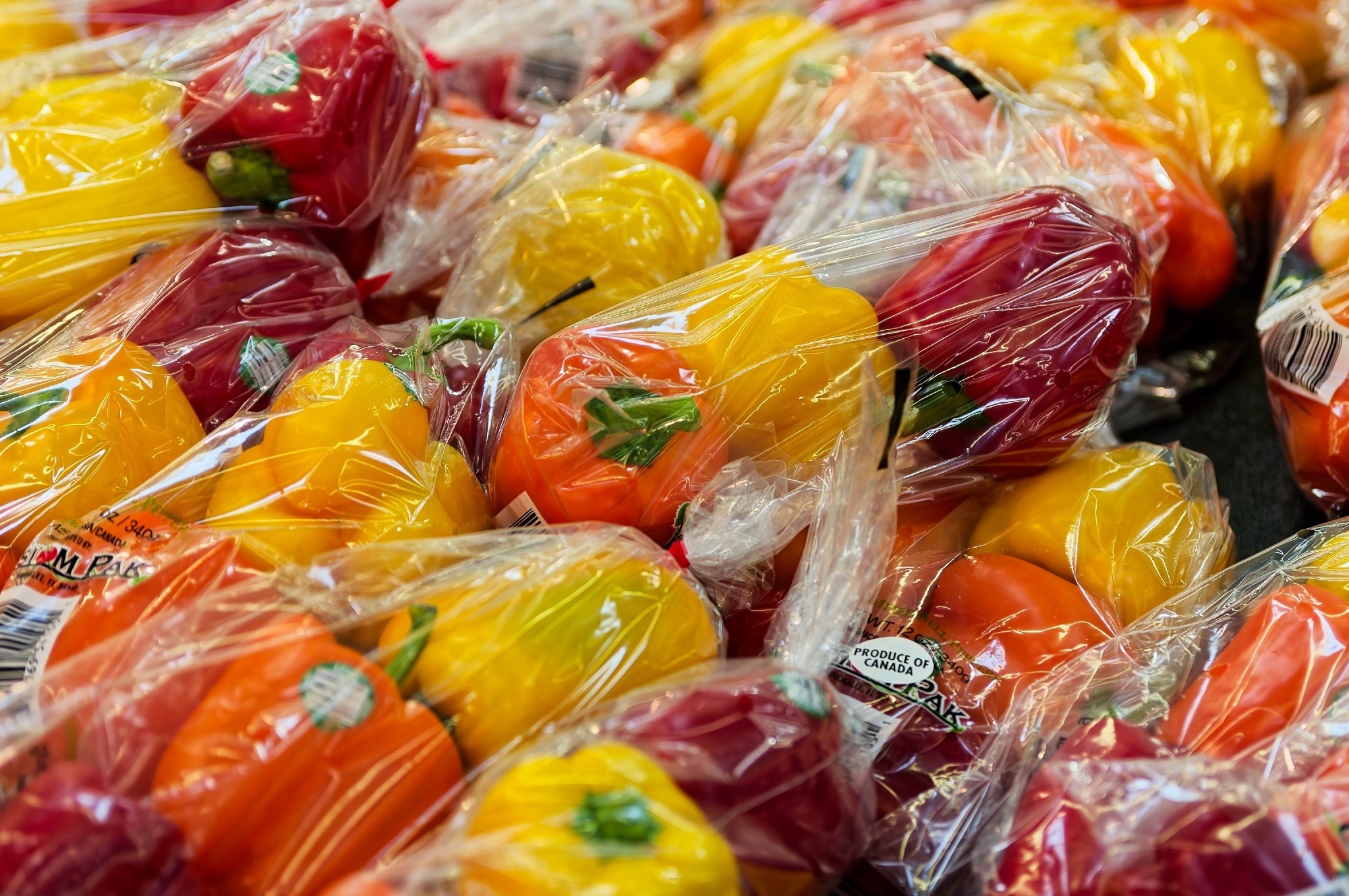 Colorful Bell Peppers Wrapped in Plastic Packaging Arranged on Grocery Store Shelf.