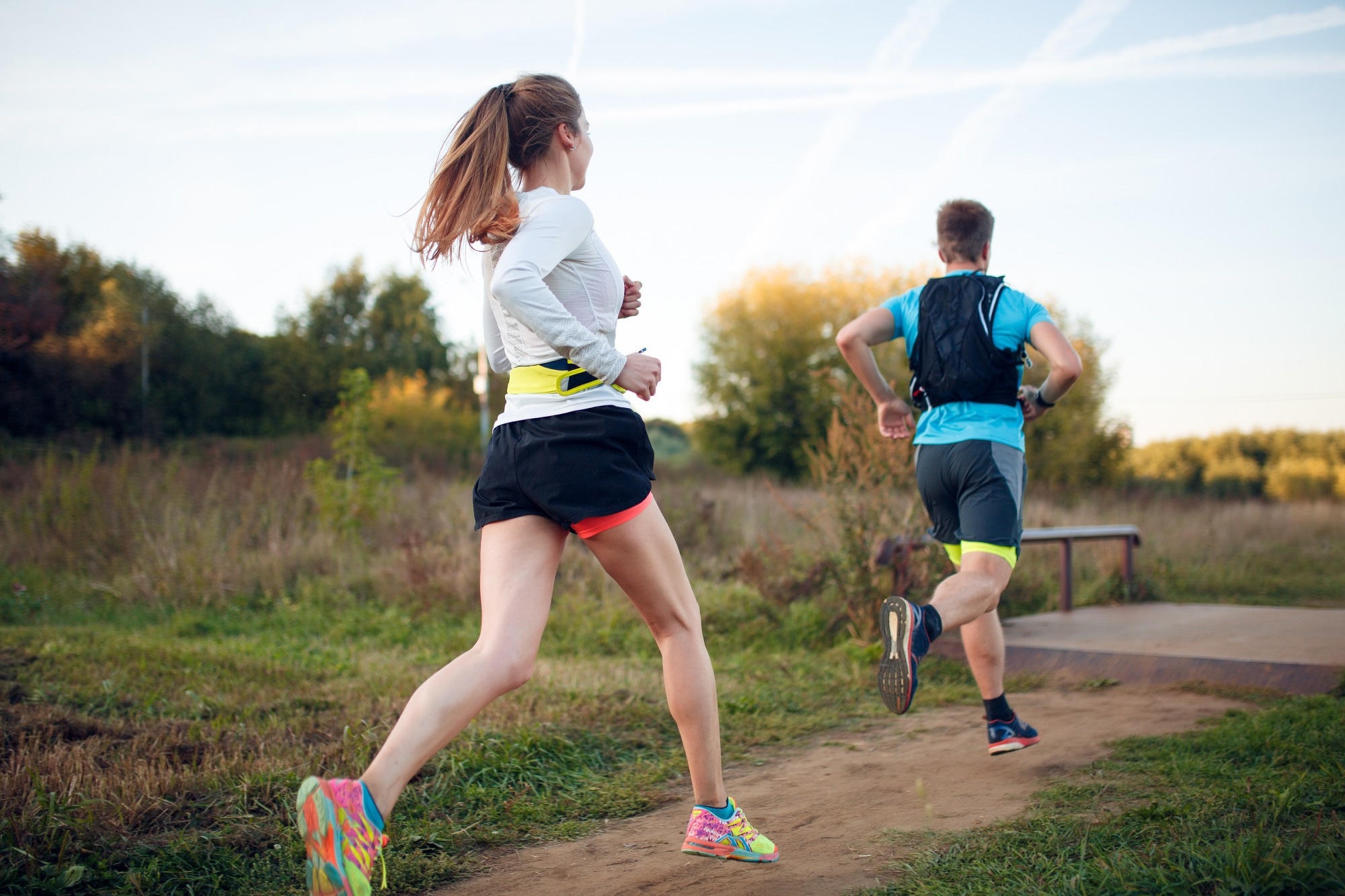 Photo on back of sportive woman and man running through park